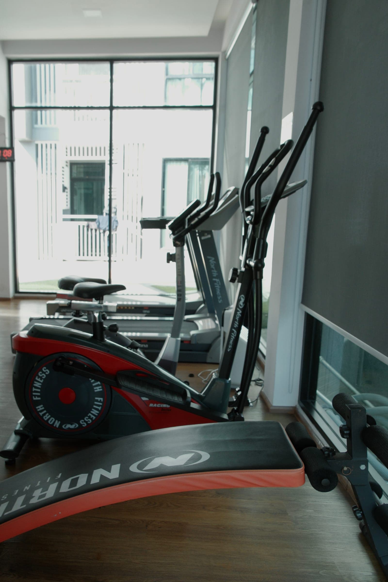 Indoor gym with treadmill, stationary bike, weight bench, and floor-to-ceiling windows